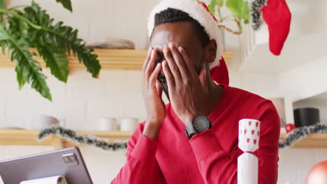 Happy-african-american-man-wearing-santa-hat,-using-tablet-for-video-call