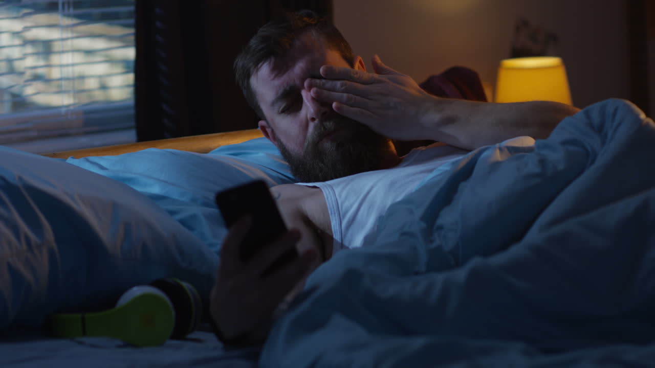 Man Lying in Bed Checking Phone at Night