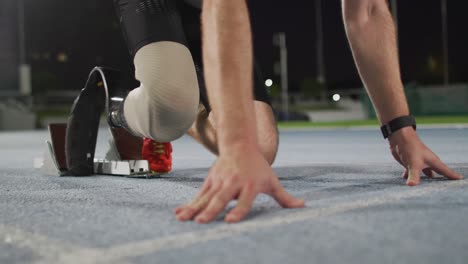 sección baja de atleta masculino caucásico discapacitado con cuchilla de correr preparándose para comenzar una carrera