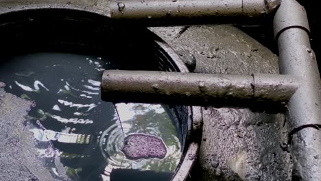 black chemical wastewater pouring on the storage tank coming out from pipe from industrial processes