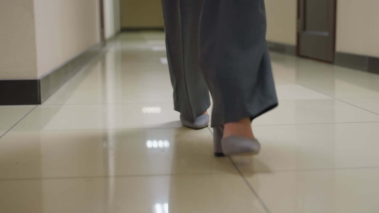 Close-up shot of businesswoman's feet in formal shoes walking through office corridor, showing professionalism, modern workspace, corporate attire, and office environment, focused on walking