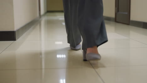 close-up shot of businesswoman's feet in formal shoes walking through office corridor, showing professionalism, modern workspace, corporate attire, and office environment, focused on walking