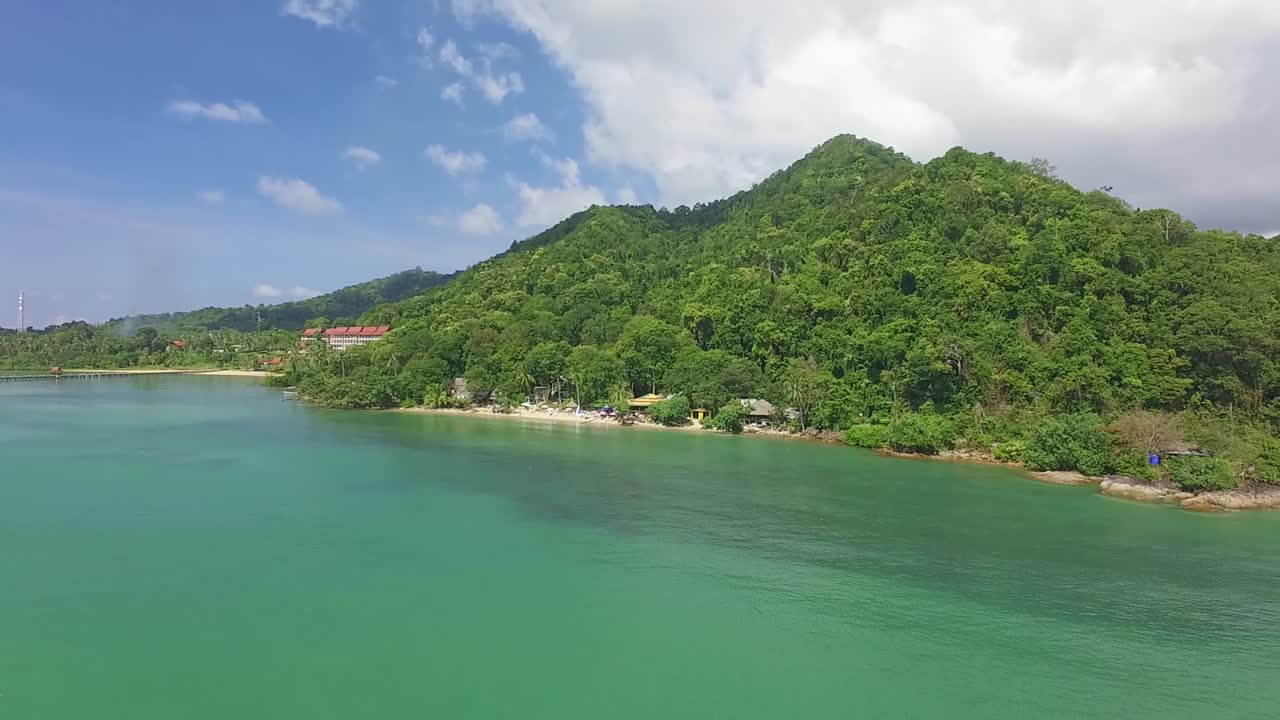toma aérea de una pequeña playa tropical en koh chang con pequeños bungalows, selva y mar turquesa