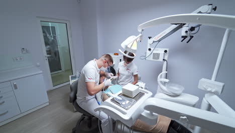 woman lies on a couch at stomatology cabinet. male doctor conducting dental check up in a modern white cabinet.