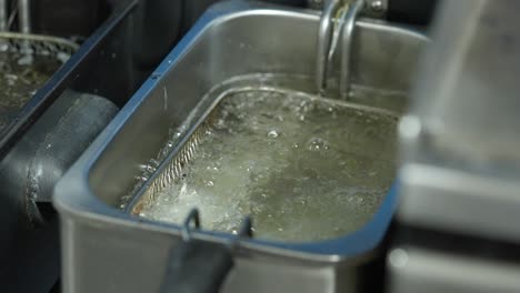 cocinero arroja un pescado rebozado en una freidora