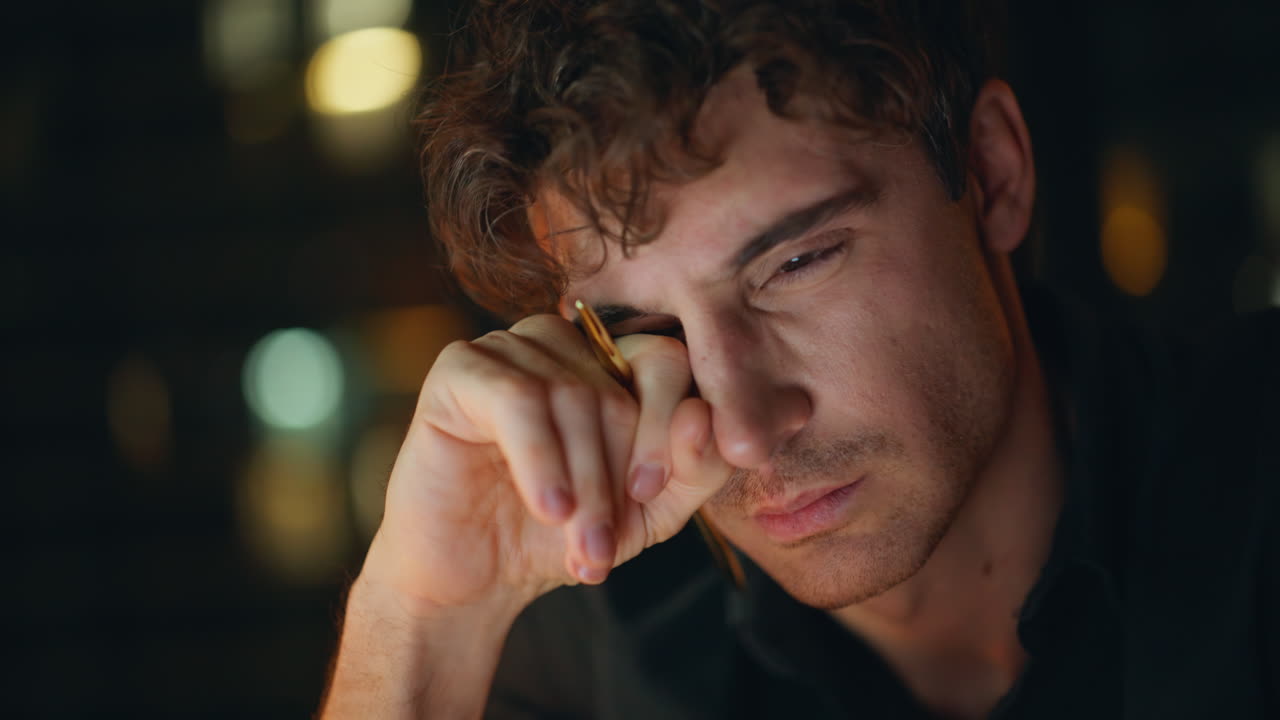 Tired businessman suffering eyestrain reviewing papers at night office closeup