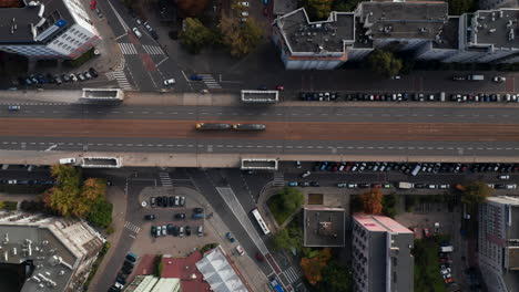 Aerial-birds-eye-overhead-top-down-panning-view-of-transport-in-city.-Tracking-of-tram-running-on-tracks-in-middle-of-wide-street.-Warsaw,-Poland