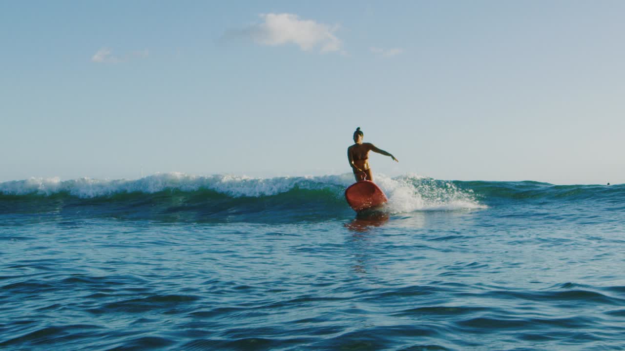 una mujer joven surfeando al atardecer.