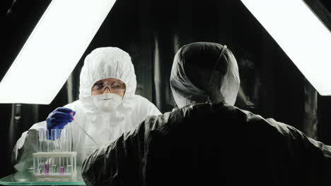 two lab technicians work in the lab dressed in protective suits