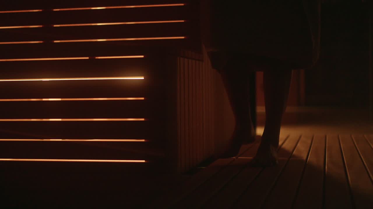 Detail ženských nohou vcházejících do útulné sauny v zimě ve wellness hotelu