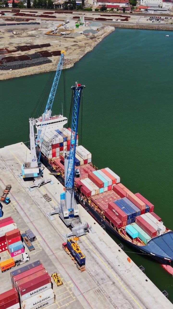 Cargo ship docks at port with containers during sunny day