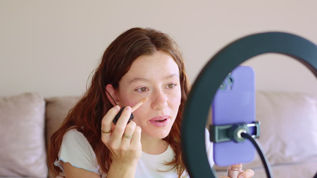 A woman applying make-up while recording a video