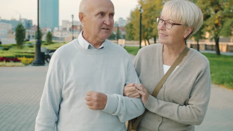 elderly couple walking and talking in park
