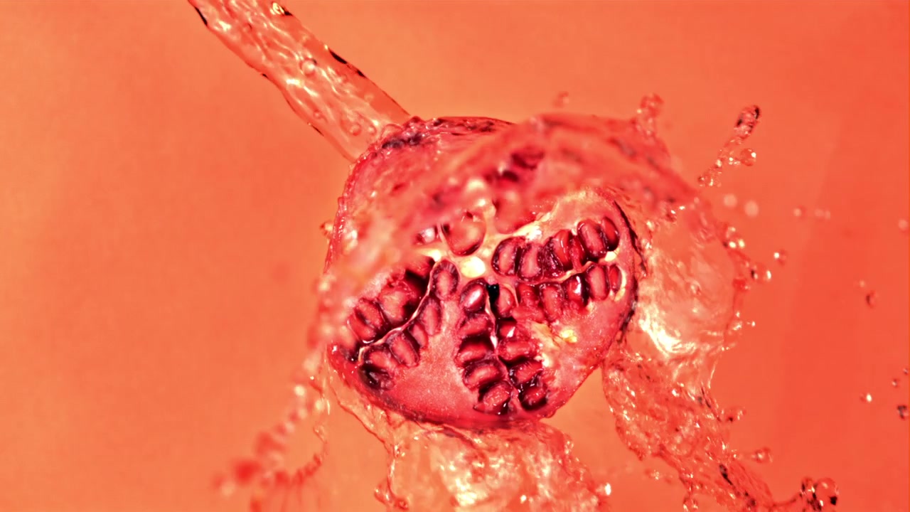 Slow Motion Juice Pouring Over a Vibrant Pomegranate Half