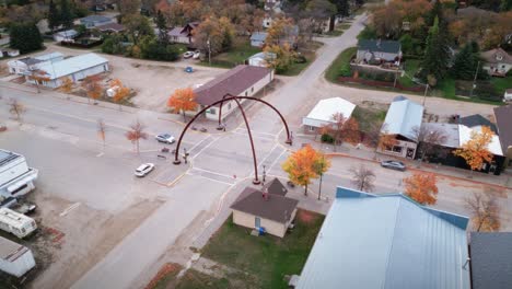 Un-Automóvil-De-Gran-Angular-Conducido-Por-Drones-Del-Paisaje-Del-Norte-De-Canadá-Un-Pequeño-Pueblo-Rural-De-Esquí-Pueblo-Pesquero-Arcos-De-La-Calle-Principal-En-La-Comunidad-De-Asessippi-En-Binscarth-Russell-Manitoba-Canadá