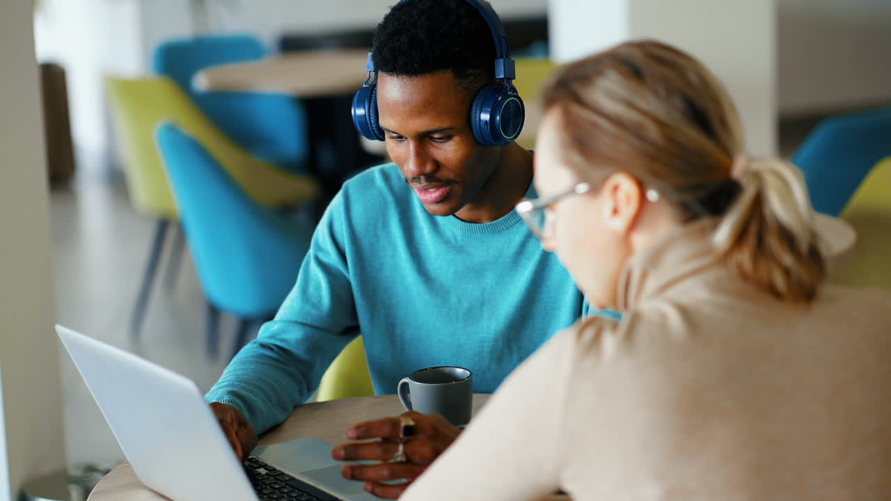 Diverse Colleagues Collaborating on Laptop in Modern Office