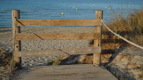 barrera de madera que bloquea el acceso a una playa de arena dorada por razones sanitarias