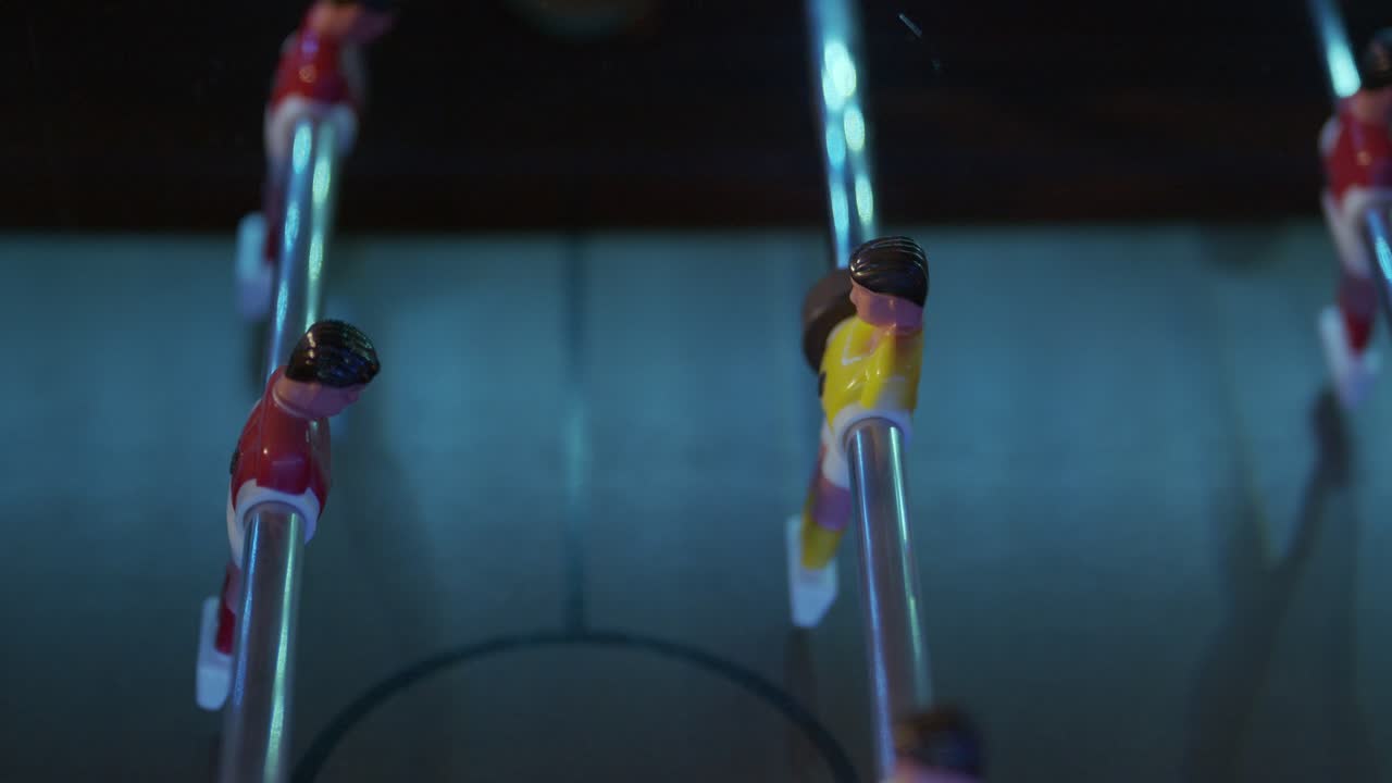 juego de mesa de futbolín disparado de izquierda a derecha, velocidad lenta, primer plano, disparo de seguimiento con jugadores de juego moviéndose