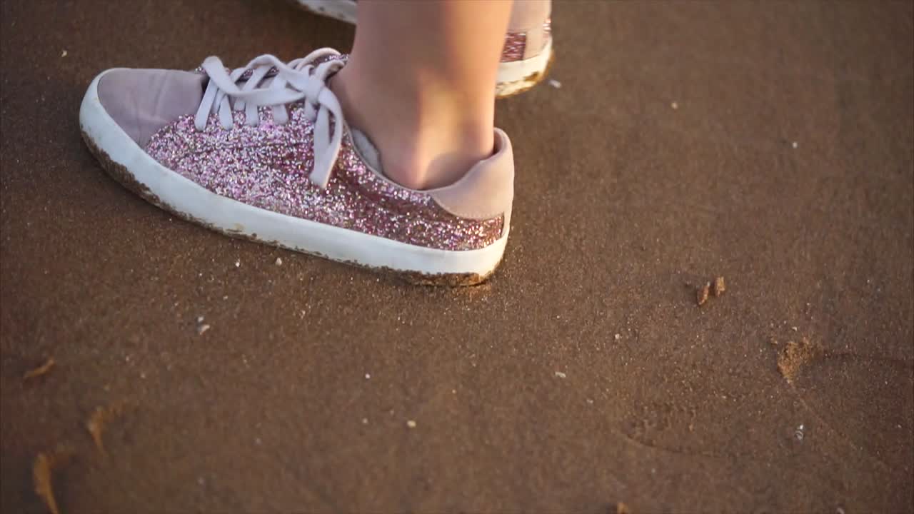 Girl's Foot in Pink Glitter Sneakers on the Beach