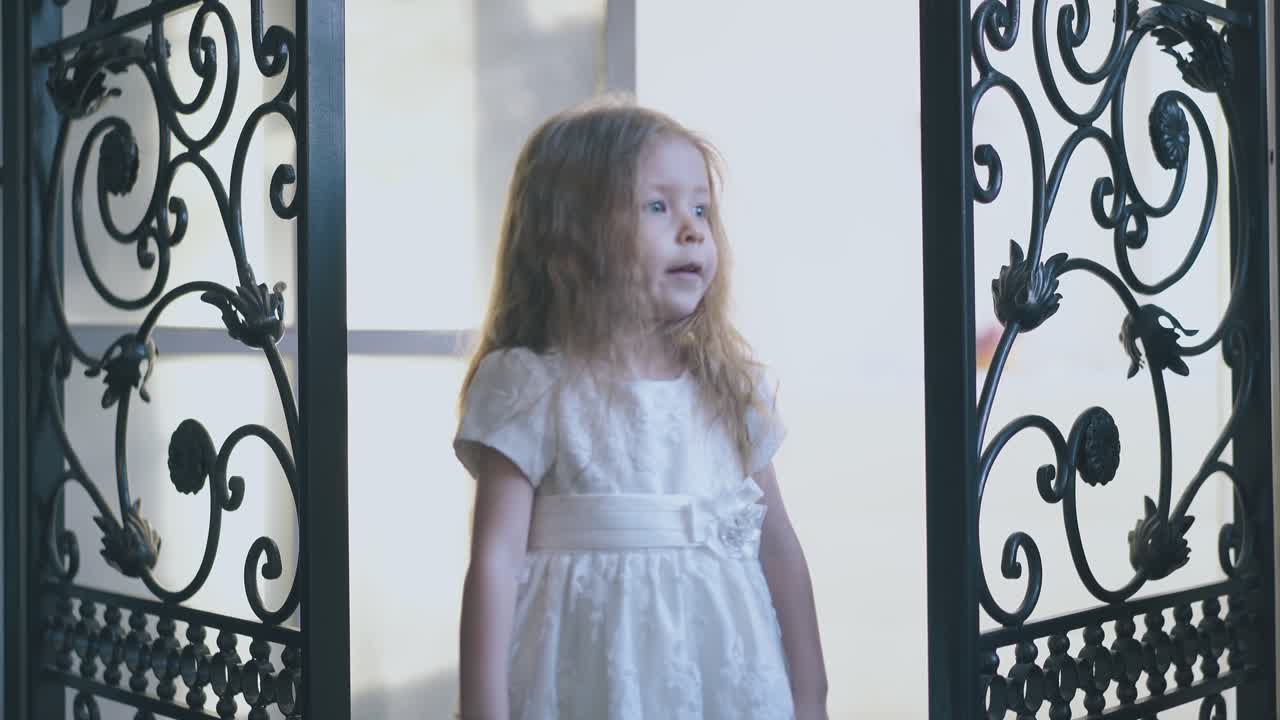 chica bonita en vestido con lazo abre celosías forjadas en la habitación