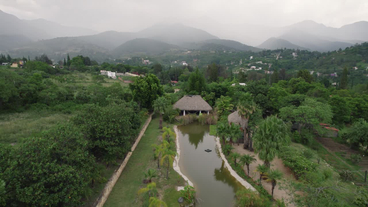 Overlooking Oaxaca's green landscape with homes, Mexico amidst mountainous backdrop - aerial