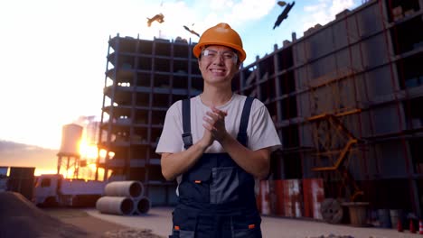 trabajador asiático aplaudiendo sus manos en el sitio de construcción