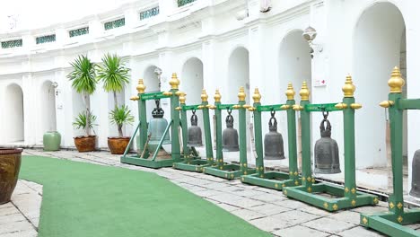 a tranquil courtyard in bangkok with lined bells and lush greenery, captured in natural daylight with smooth camera movement