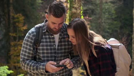 couple hiking in forest using smartphone