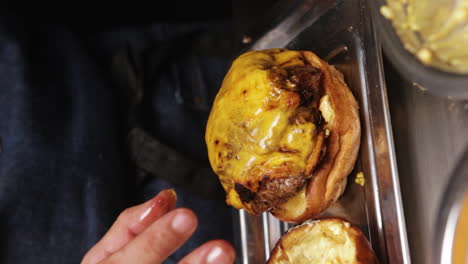 chef placing burger patty with melted cheese on top on burger bun