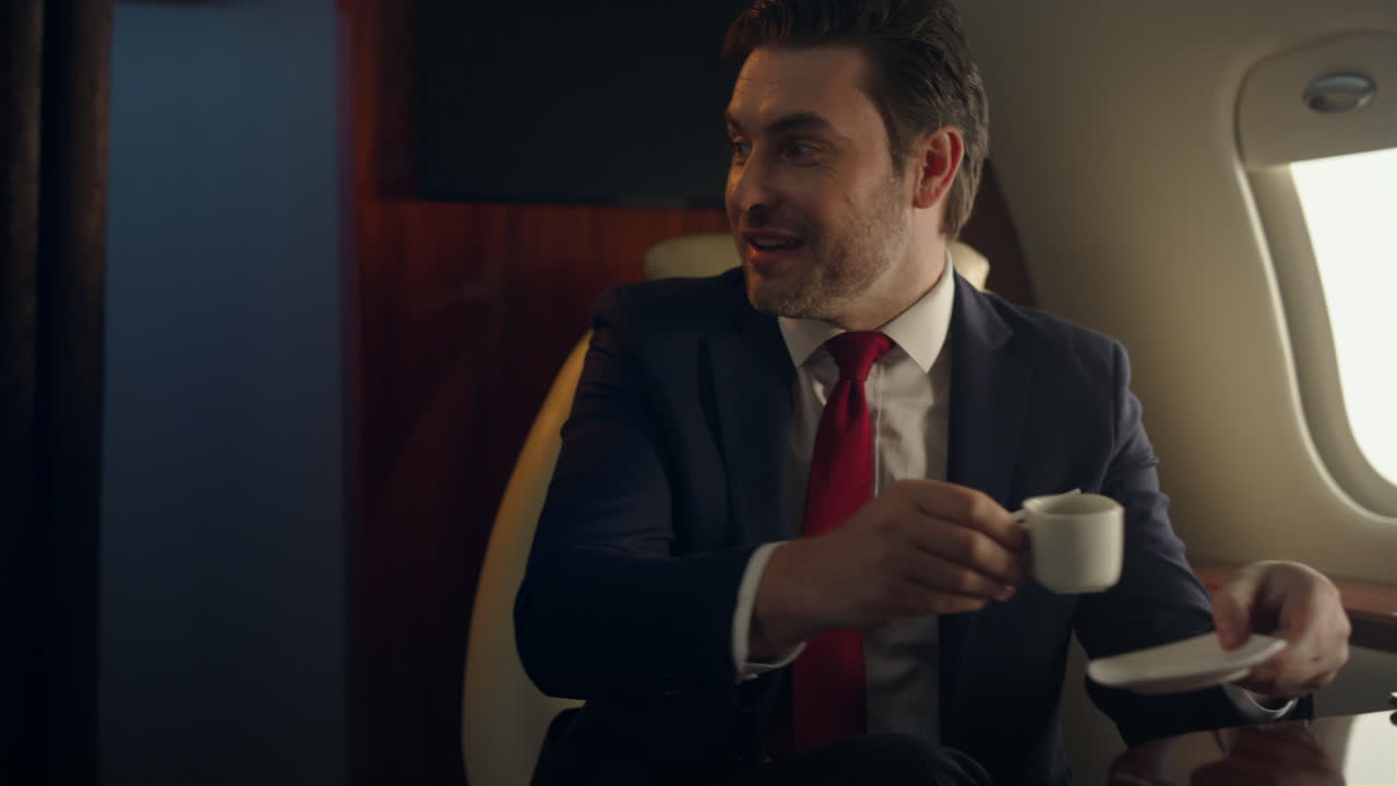 Uomo sorridente in jet per viaggio aziendale, primo piano. Dirigente felice beve caffè.