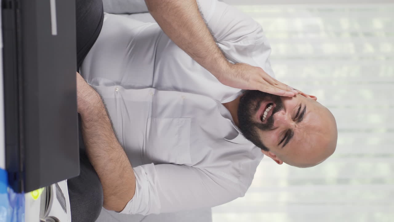 Vertical video of Home office worker man teeth aches and pains.