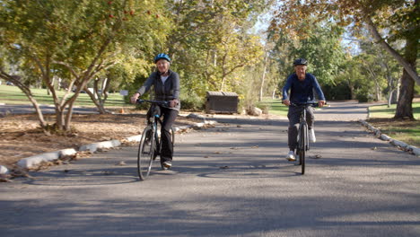 senior couple cycling through park in slow motion