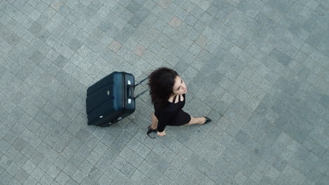 Top-view-of-confident-woman-walking-with-suitcase-outdoors