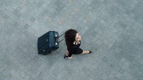 top view of confident woman walking with suitcase outdoors