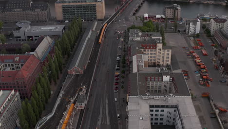 AERIAL:-Flight-over-Berlin,-Germany-at-beautiful-Sunset,-Sunlight-and-view-Warschauer-Strasse-in-Dusk