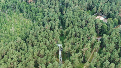 cable cart pole with moving carts surrounded by dense conifer forest in druskininkai, aerial view