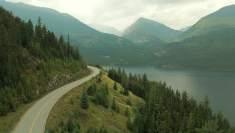 aerial shot of slocan lake with a road wrapping around