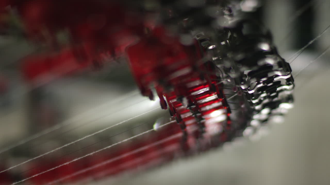 Cotton threads travel through gears of an automated textile knitting machinery in textile factory in China