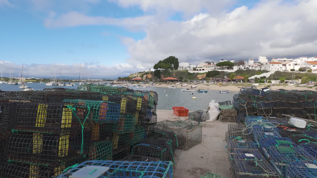 Stacked lobster pots laying on the pier in a fishing harbor in Alvor, Portugal, with boats moored in the background