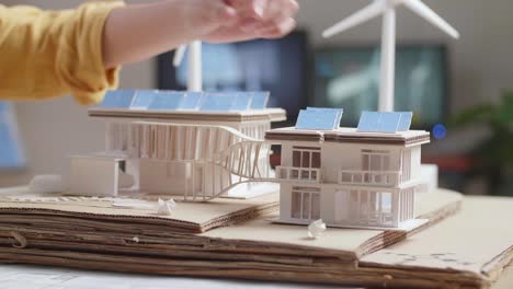 architectural model of a sustainable home with solar panels and wind turbine