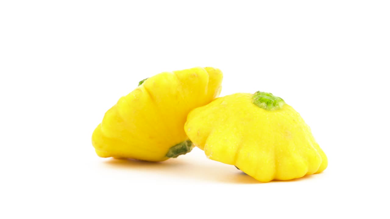 dos calabazas patisson amarillas. girando en la mesa giratoria. aisladas en el fondo blanco. primer plano. macro.