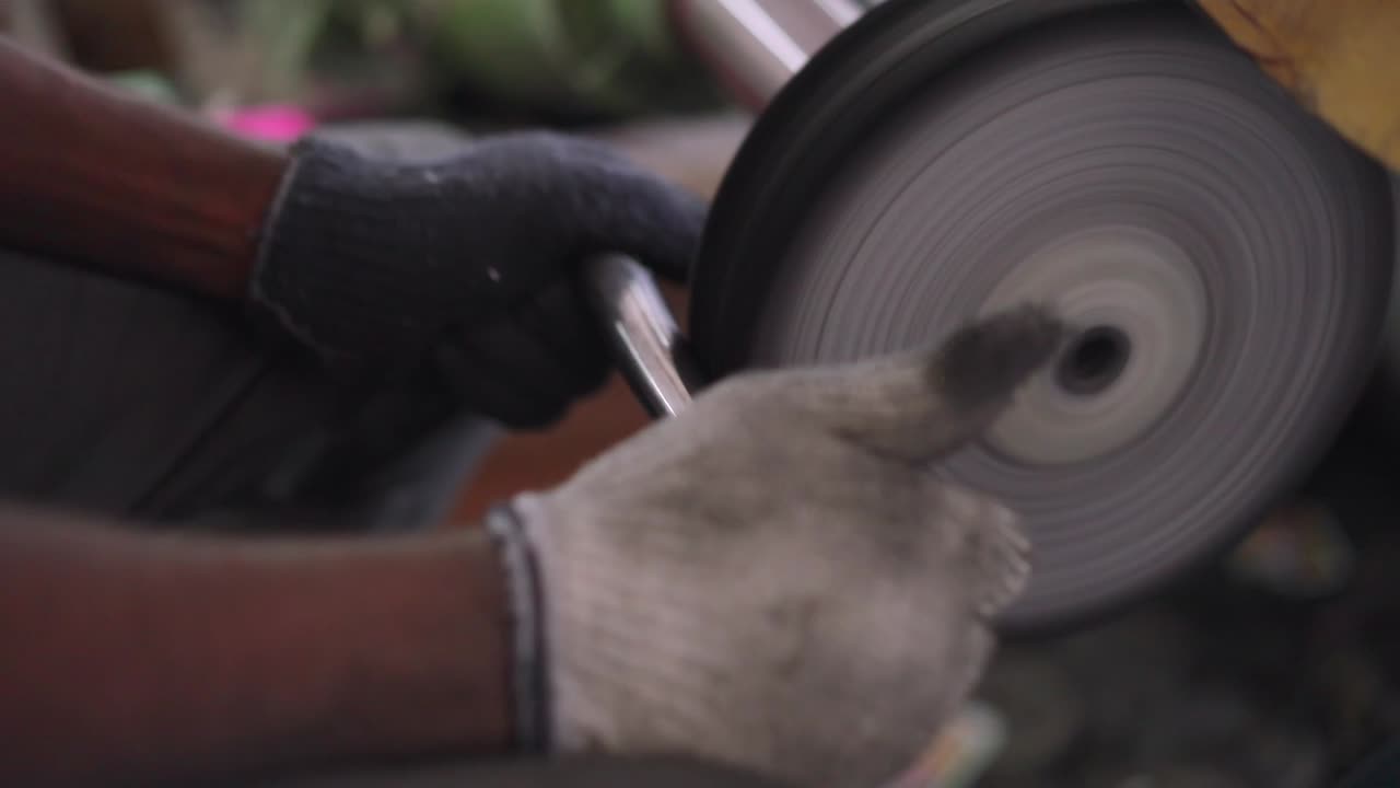 Using a belt sander to produce steel pan cookware in a factory