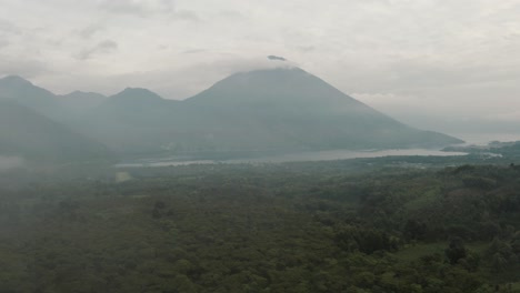 light fog covering the green forest, lake atitlan and the volcanoes in guatemala