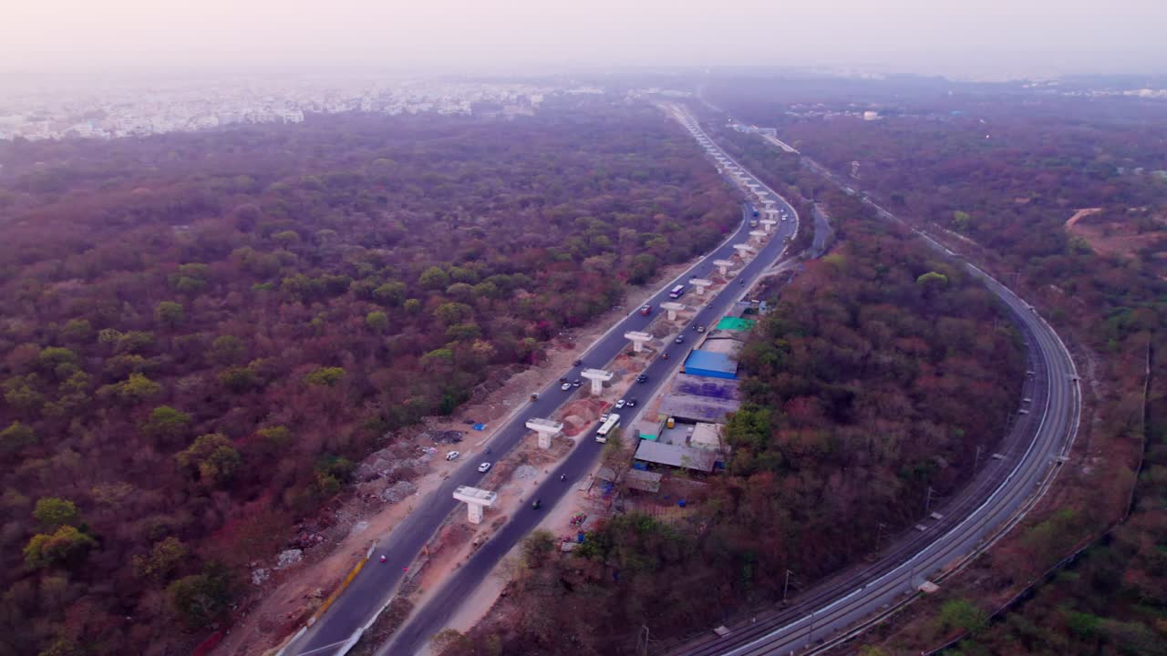 Under construction flyover with railway track and trees at suchitra, hyderabad, telangana, india. day time, semi orbit, drone shot, 4k.