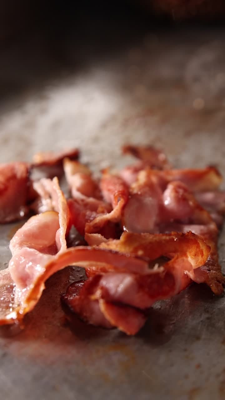 Primo piano di pancetta che frigge e sfrigola su una piastra calda