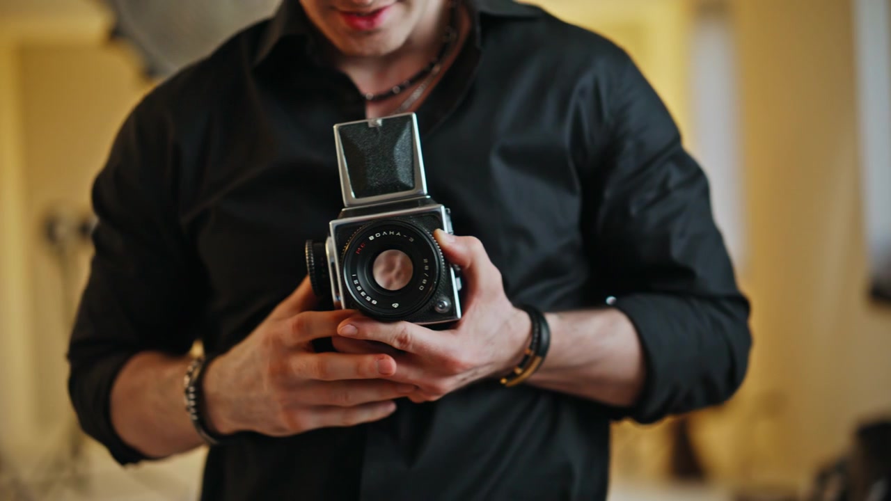 Uomo che mostra una macchina fotografica retrò, mani in primo piano. Fotografo che parla a casa
