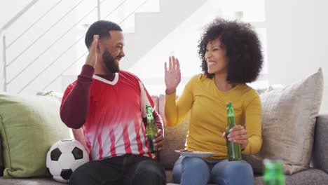 couple cheering while watching sports on tv at home