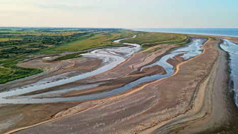 Entdecken-Sie-Den-Idyllischen-Charme-Einer-Küstenszene-Zur-Goldenen-Stunde-Durch-Atemberaubende-Drohnenaufnahmen-Aus-Der-Luft:-Flussmündung,-Sandbänke,-Meer-Und-Marschland