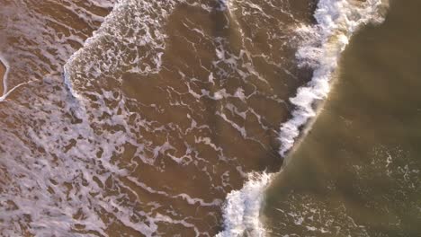 spinning slow motion birds-eye view of waves breaking in the sandy shore in a caribbean sea beach