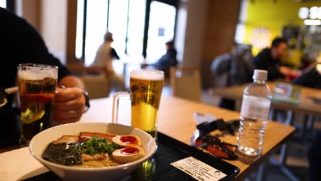 persona comiendo ramen y bebiendo cerveza en la mesa